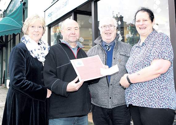 The winner of the Porthmadog Christmas Window competition for charity shops was the St David's Hospice shop. Pictured is manager Janine Mander being presented with her prize by judges Angela and Bill Swann and Cllr Selwyn Griffiths