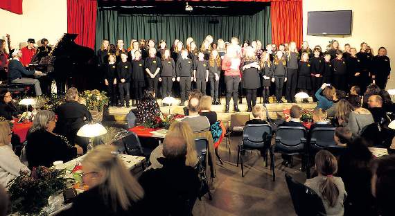 The school choir, along with head teacher Helen Lewis, entertain the crowded school hall