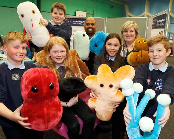 Ysgol Llanilar pupils Iwan Simpson Jones, Swyn Jones, Owen Howard, Chantelle Griffiths, and Harvey Matthews with their teacher Ceri Jones, and microbiology PhD student Paul Livingstone and models of infections, bacteria and fungi viruses