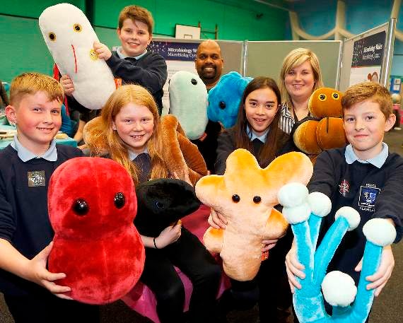 Ysgol Llanilar pupils Iwan Simpson Jones, Swyn Jones, Owen Howard, Chantelle Griffiths, and Harvey Matthews with their teacher Ceri Jones, and microbiology PhD student Paul Livingstone and models of infections, bacteria and fungi viruses