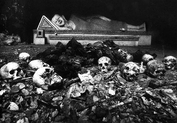 Cambodia, 1980. Roedd y Bwda hwn yn gorwedd mewn ogof o dan deml ger tref Sisophon, gyda gweddillon nifer o bobl Cambodia o'i gwmpas. Roedd milwyr o Fietnam wedi goresgyn yr ardal ychydig yn gynt