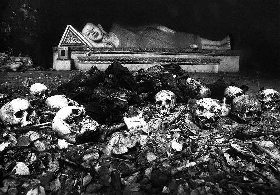 Cambodia, 1980. Roedd y Bwda hwn yn gorwedd mewn ogof o dan deml ger tref Sisophon, gyda gweddillon nifer o bobl Cambodia o'i gwmpas. Roedd milwyr o Fietnam wedi goresgyn yr ardal ychydig yn gynt