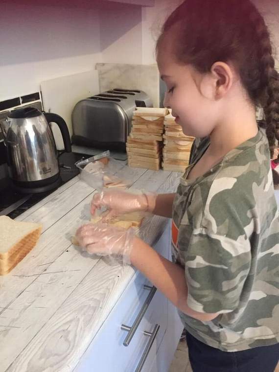 Baileigh-Rae, 8, helping make up packed lunches for children in the Liskeard area who might need them