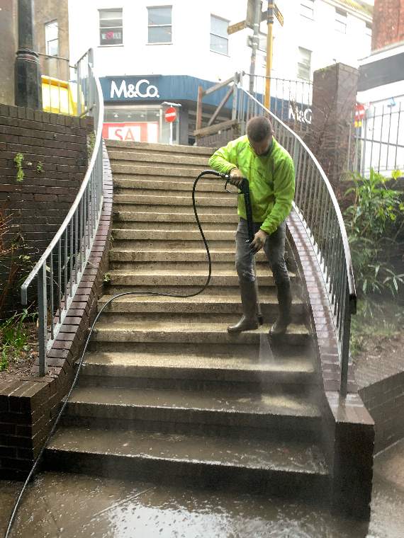 Paul Caers washing the steps between Fore Street and Poundland
