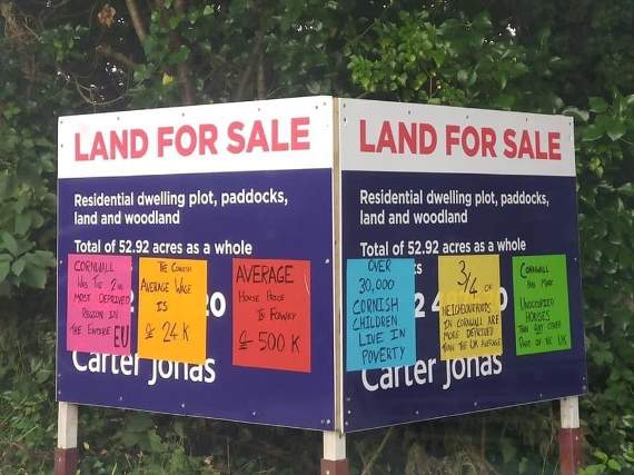 Stickers on a land for sale sign in Fowey reflect the feelings mounting in Cornwall about housing