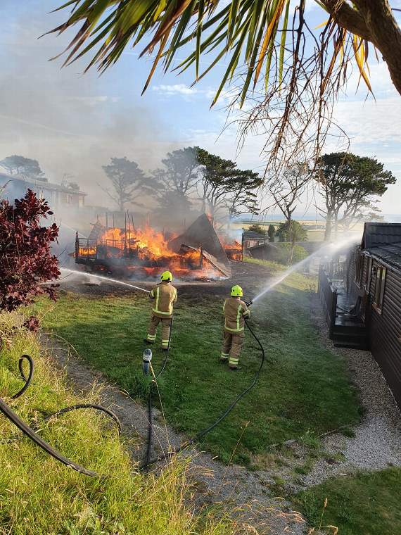 Fire crew damping down surrounding chalets to prevent them catching light from the one where the fire began in a fridge