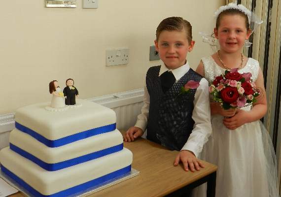 After the mock wedding at the Parish Church the bride and groom Breya Davey and Bradley Linton are pictured beside the wedding cake during the reception at the Boniface Centre. NP 100715 11