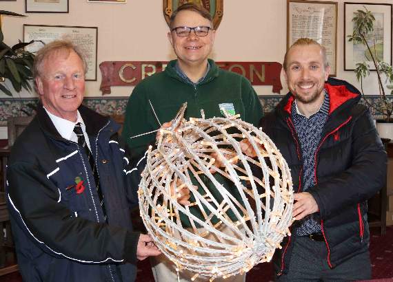 New lights will be displayed in Crediton’s Town Square as part of the Christmas in Crediton committee’s increase in lights this year, including 20 spherical globes like this one held by, from left, Mike Overfield-Collins, Phil Cork and Benji Evans of Crediton Dairy. AQ 5531