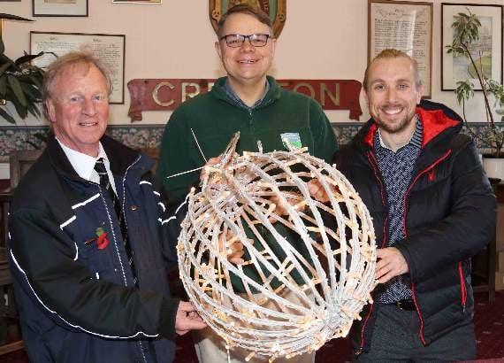 New lights will be displayed in Crediton’s Town Square as part of the Christmas in Crediton committee’s increase in lights this year, including 20 spherical globes like this one held by, from left, Mike Overfield-Collins, Phil Cork and Benji Evans of Crediton Dairy. AQ 5531