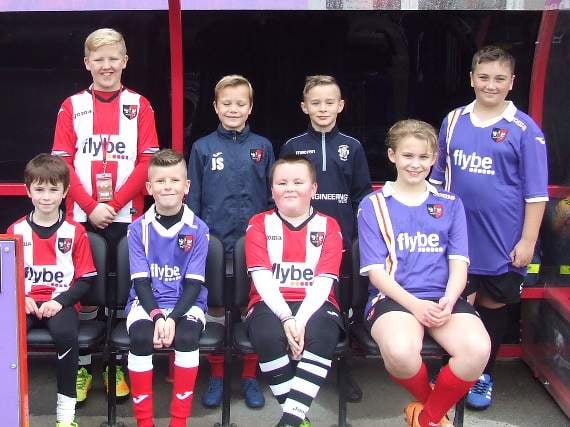 Crediton’s two match mascots, Josh Saunders and Frankie Mason, back row, centre, with others pictured in the dug out at Exeter City’s St James’ Park.