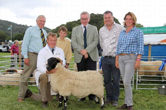 The Secretary of State for Environment, Food and Rural Affairs, the Rt Hon Michael Gove, fourth left, met three generations of Dartmoor farmers at Chagford Show, left, John Jordan, Robert Jordan holding one of the family’s prizewinning sheep, Jack Jordan (11), with Rt Hon Mel Stride, MP for Central Devon, fifth left and Rebecca Jordan, right. AQ 3408