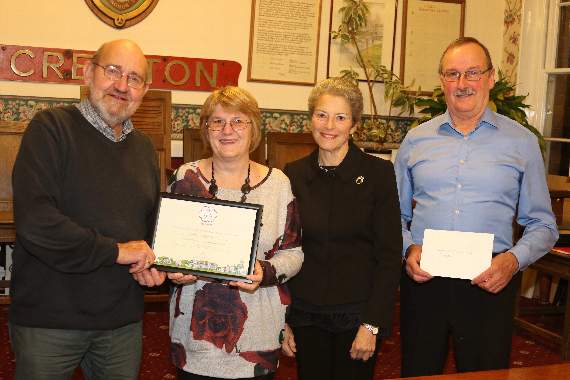 Bert and Margaret Jewell, left, receiving the Friends of Crediton Town Square It’s Your Neighbourhood Britain In Bloom South West competition award from Lynette Talbot, RHS Judge and Chair of Sidmouth In Bloom with Cllr Michael Szabo, Chairman of the Floral Crediton committee, right. AQ 5211