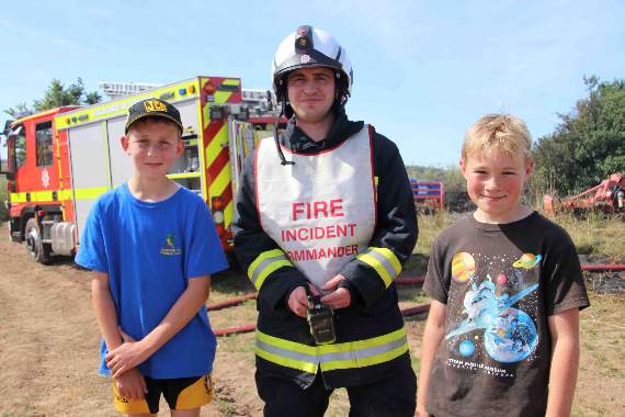 Nathan Saunders, left and Finlay Stanton, right, both aged 11, who have been praised for helping to prevent a serious farmland fire from developing by Crediton Watch Manager Neil Hargreaves, centre. AQ 2570