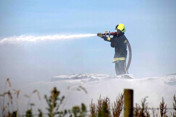 A firefighter using compressed air foam to put out the fire involving tyres on the silage pit which was involved in the fire. AQ 2544