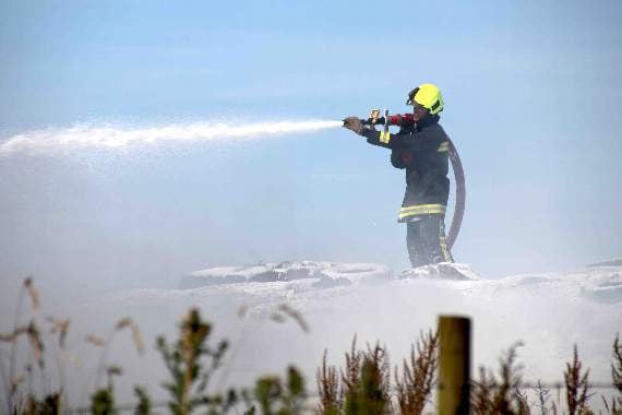 A firefighter using compressed air foam to put out the fire involving tyres on the silage pit which was involved in the fire. AQ 2544