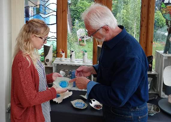 Girts Gailans in venue C explains to a visitor a decorative technique on one of his ceramic pieces.