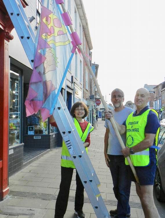 Rosemary Stephenson (Chair of Crediton Town Team), David Oliver and Paul Fallon (President of the Rotary Club of Crediton Boniface) putting up flags along Crediton High Street. NP 310519 08