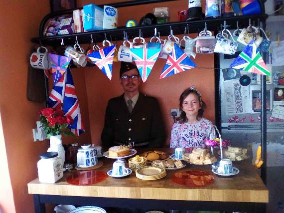 Brownie Thora Cliffe-Duffield having tea on VE Day with her dad who is appropriately dressed for the occasion.