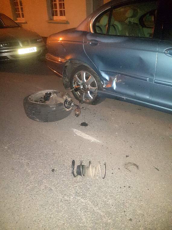 One of the parked vehicles involved in the collision and a wheel from one vehicle.