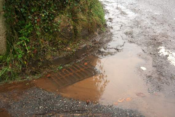 A blocked drain on the corner of the junction with the road from Copplestone into New Buildings. 3502