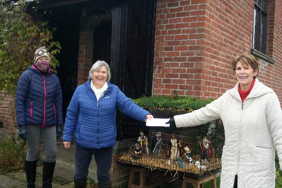 In front of the nativity tableau at Yeoford Holy Trinity Church are Carol Price (centre) receiving a cheque from League of Friends chairman, Louise Adams (right) and helper, Dee Elston. 3439