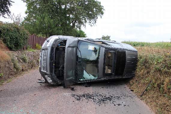 The Land Rover vehicle on its side on Higher Road, Crediton. AQ 3799