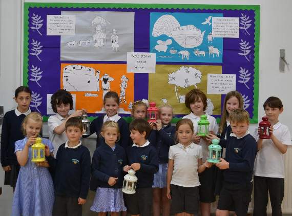 A group of Medstead pupil worship leaders with their lanterns which they bring into the hall from class as a symbol of togetherness for assemblies. The children are pictured with the illustrations they created for the Bible stories focused on in the summer term to help children understand the value of hope