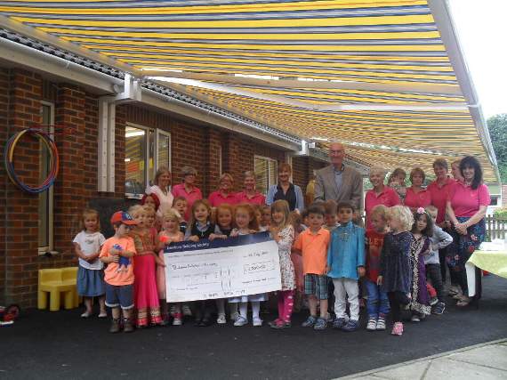 Pupils display a cheque presented to the pre-school by Medstead Summer Ball