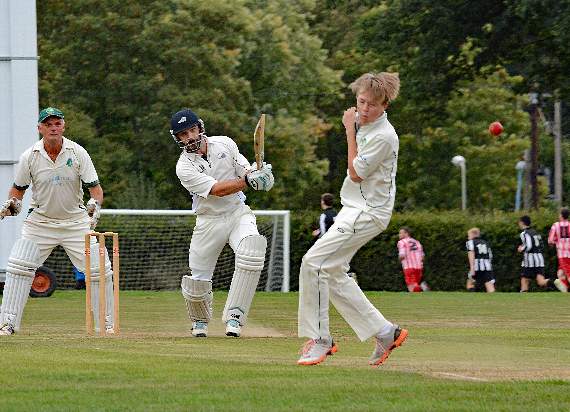 Sensible chap: Harting youngster Archie Wadey takes evasive action as Farncombe’s Richard Baker hammers the ball back at him. Apprehensive uncle Terry Wadey watches from behind the stumps. (photo Anthony Ainslie)