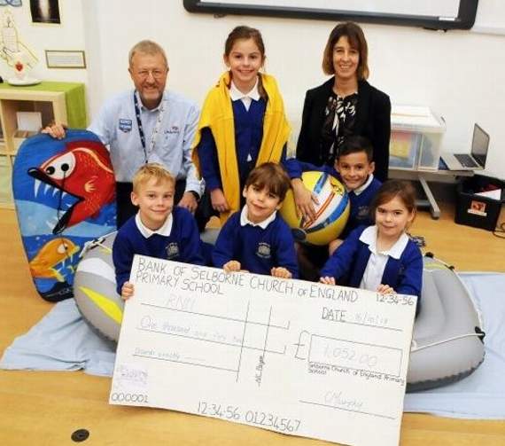 Selborne Primary School headteacher Claire Murphy and pupils are all smiles after handing over the £1,052 cheque to Brian Masters of the RNLI