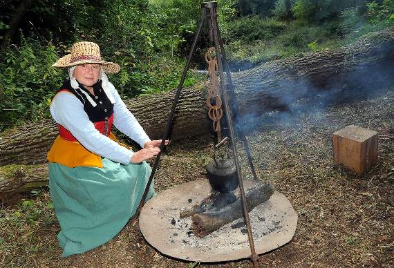 Julie Walker in period costume by the kettle warmed over the fire (HD39-95-18)
