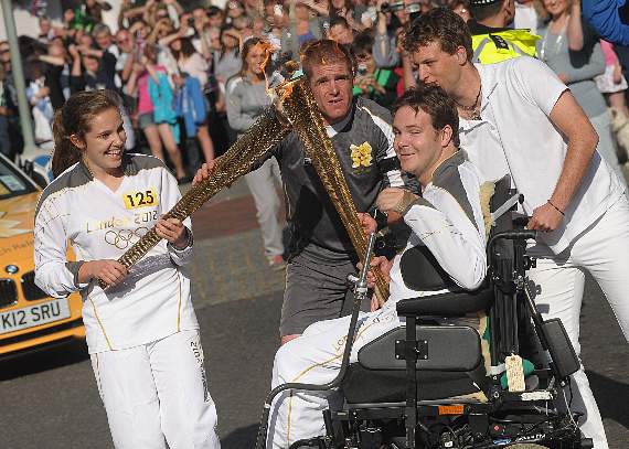 Witley charity founder Dan Eley and Hampshire’s Roger Black, who won an Olympic silver medal in the 400 metres at the 1996 Atlanta Games, carry the Olympic torch through Godalming in 2012