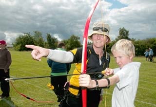 Instructor Cherry Lyne helping Jake Morris in his first attempt at archery.
