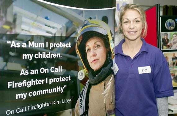 Firefighter Kim Lloyd stands beside a dramatic poster of herself.