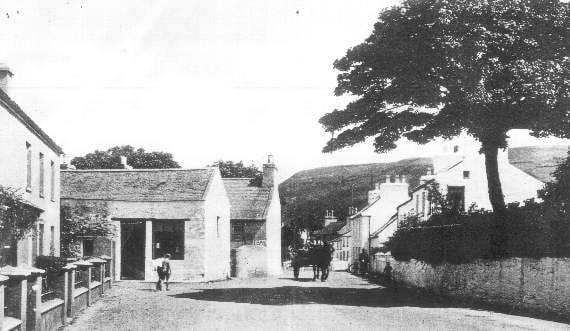 A late Victorian or Edwardian view of the road past the milliner’s and butcher’s shops and The Albert