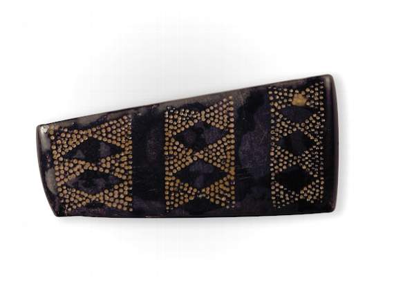 A decorated jet spacer plate from the bead necklace, showing diamond-shaped design. The bead is wet to keep it stable