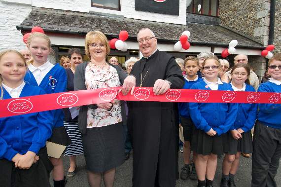 OFFICAL OPENING: Postmaster Lorraine Lee cuts the ribbon, with the help of the Abbot of Buckfast, David Charlesworth, and watched by primary school pupils.