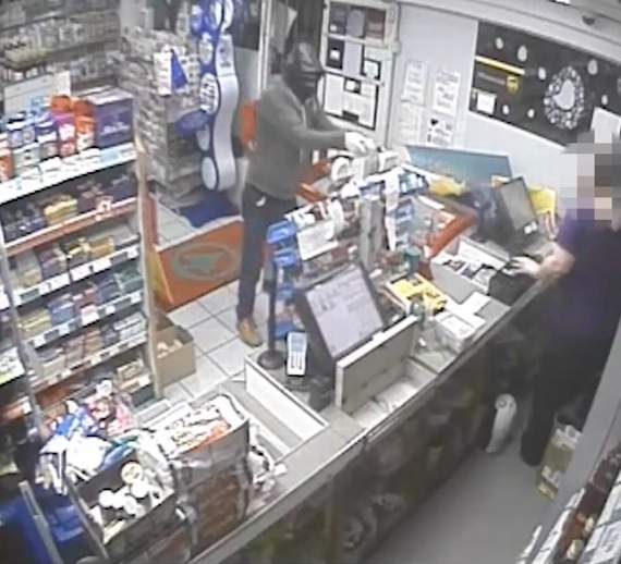 A masked Lee Bidmead is pictured spraying a female employee with petrol at the Spar store in Portskewett