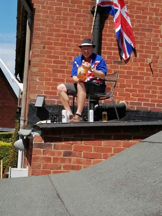 Darren Brennan celebrated the day on his porch roof so he could see all the parties in his street in Harting