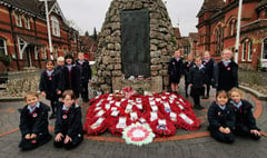 Children lay their hand-made wreath on war memorial