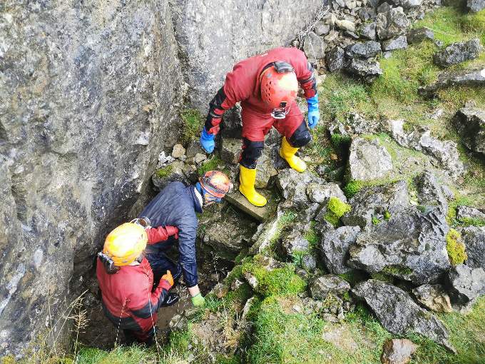One of the men exiting the Daren Cilau cave system following the rescue and below rescue teams working together to evacuate a man with a dislocated hip at Ogof Clogwyn