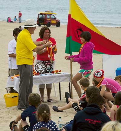Chairman of Tenby Surflink Jules Rilstone presents the winners shield to Poppit Sands Surf Lifesaving Club.