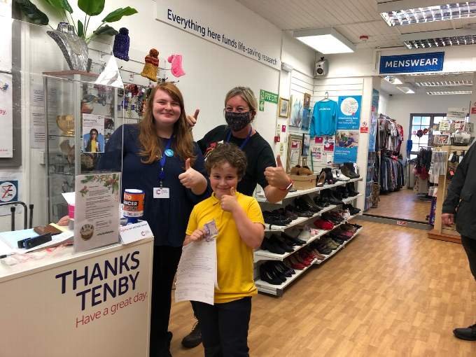 Eight-year-old Henry with Kayley and Sally, staff members of Cancer Research.