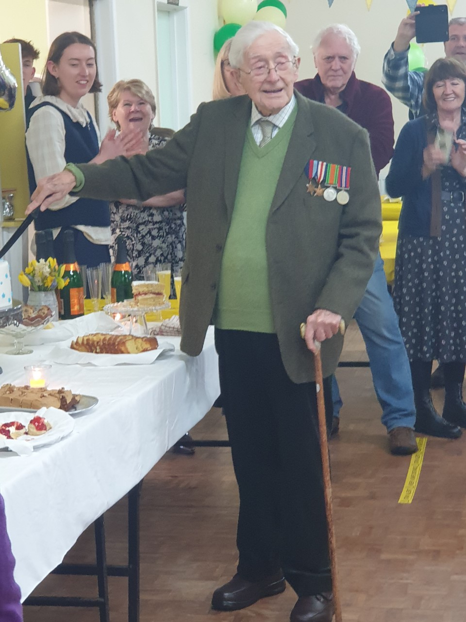 John Gwynne cuts his 101st birthday cake, surrounded by family and friends