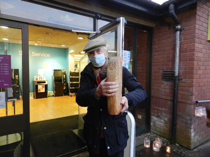 Paul Cleave carrying his carved fragment into Crediton Library ready for the bench to be assembled. NP 160122 03