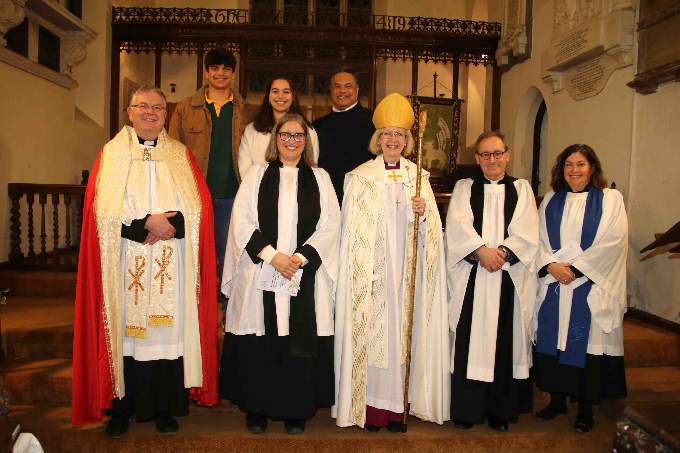 Rev Janet May, front row, second left, with, centre, the Bishop of Crediton, the Rt Rev Jackie Searle, with left, the Archdeacon Andrew Beane, and right, Rural Dean, the Rev Matthew Tregenza and Deanery Lay Chair, Laura Armstrong. Back row is Janet’s husband Alfred and their children. AQ 5236