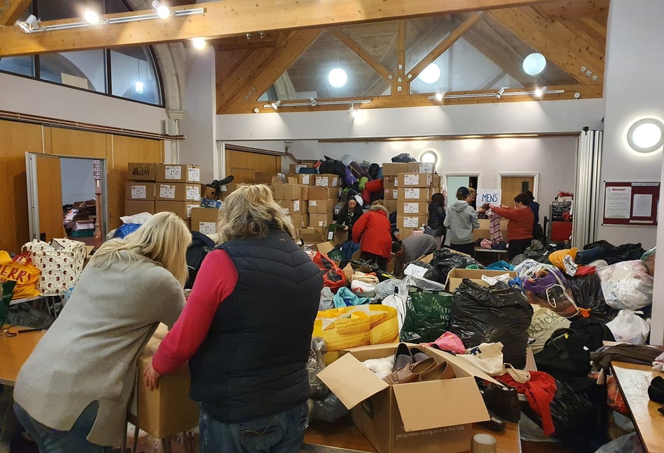 <p>Masses of Farnham Help for Refugees volunteers rolled up their sleeves to help sort the mountain of donations at St George’s Church in 2023</p>