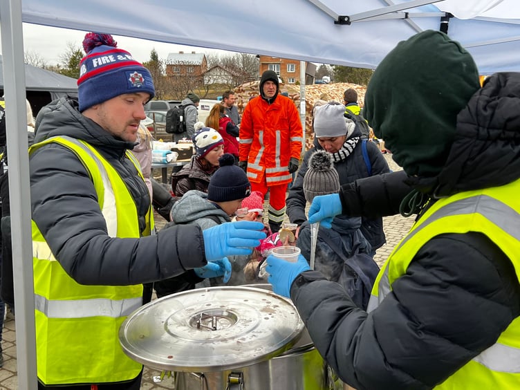 Serving a hot chicken and potato dish to refugees