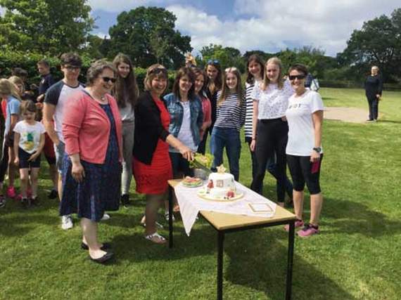 The cutting of the cake. Two of the three current members of staff who are still with Halwill School having moved from the old school site to the new one in Halwill Junction are pictured with parents and ex pupils.