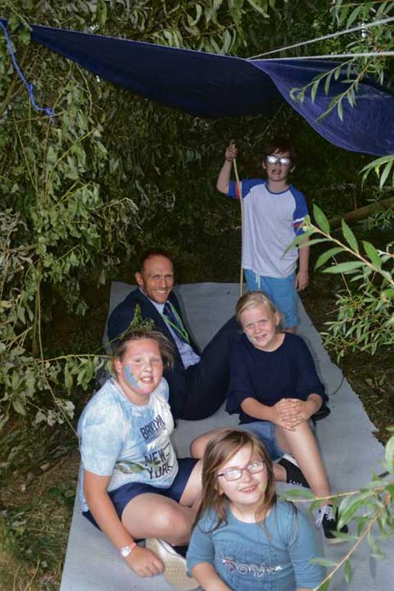 The primary executive head teacher of the Dartmoor Federation; Phil Whittley in a den made by the children.